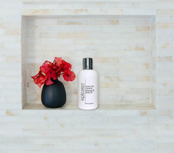 Epicuren Discovery Kukui Nut Coconut Massage & Body Oil bottle surrounded by tropical leaves and spa elements.