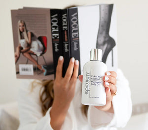 Epicuren Discovery Kukui Nut Coconut Massage & Body Oil in a bottle, surrounded by tropical coconut and kukui nuts.