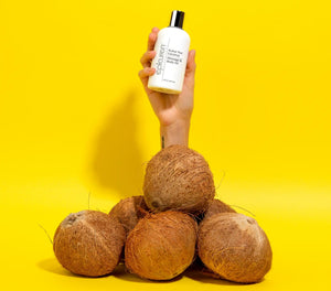 Epicuren Discovery Kukui Nut Coconut Massage & Body Oil in an 8 fl oz bottle, surrounded by tropical elements.