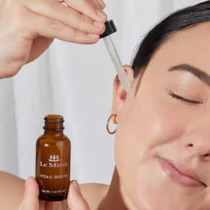 Le Mieux Vita-C Serum in a glass bottle with dropper, featuring vibrant orange citrus design, for brightening and skincare.