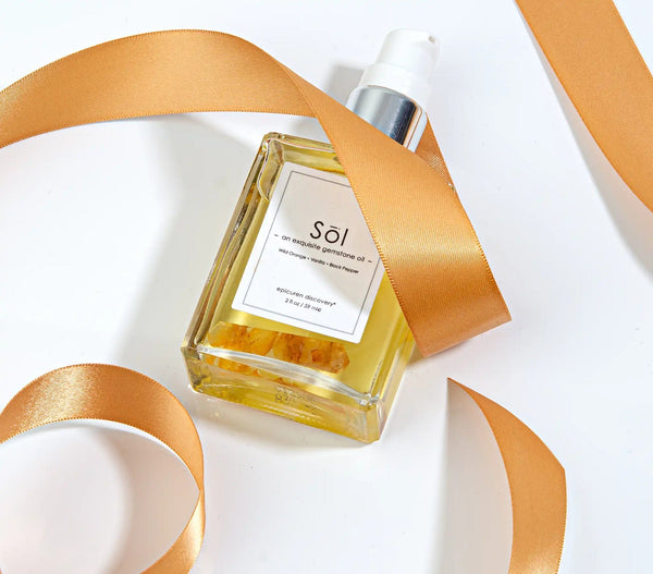 Epicuren Discovery Sol Exquisite Gemstone Oil in a 2oz bottle, surrounded by natural elements for aromatherapy.