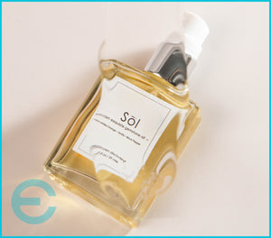 Epicuren Discovery Sol Exquisite Gemstone Oil 2oz in a glass bottle with gemstones, set against a serene lifestyle backdrop.