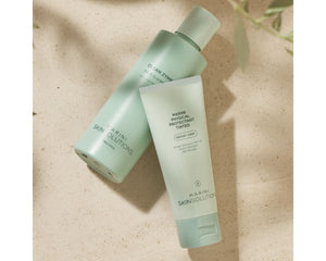 Jan Marini Clean Zyme cleanser in a lifestyle setting with a bottle and soft towel on a bathroom countertop.